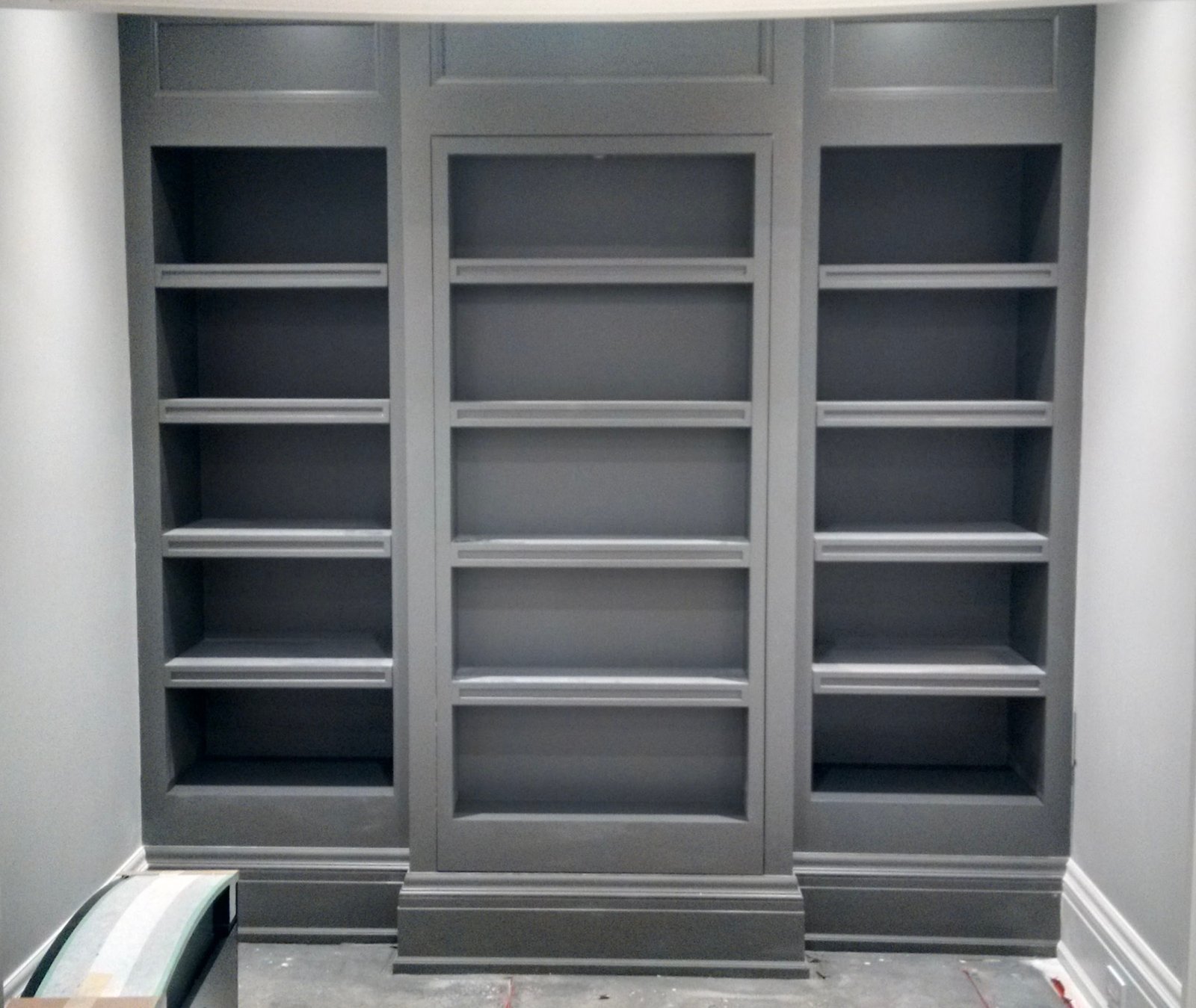 Custom grey built-in shelving with a concealed door